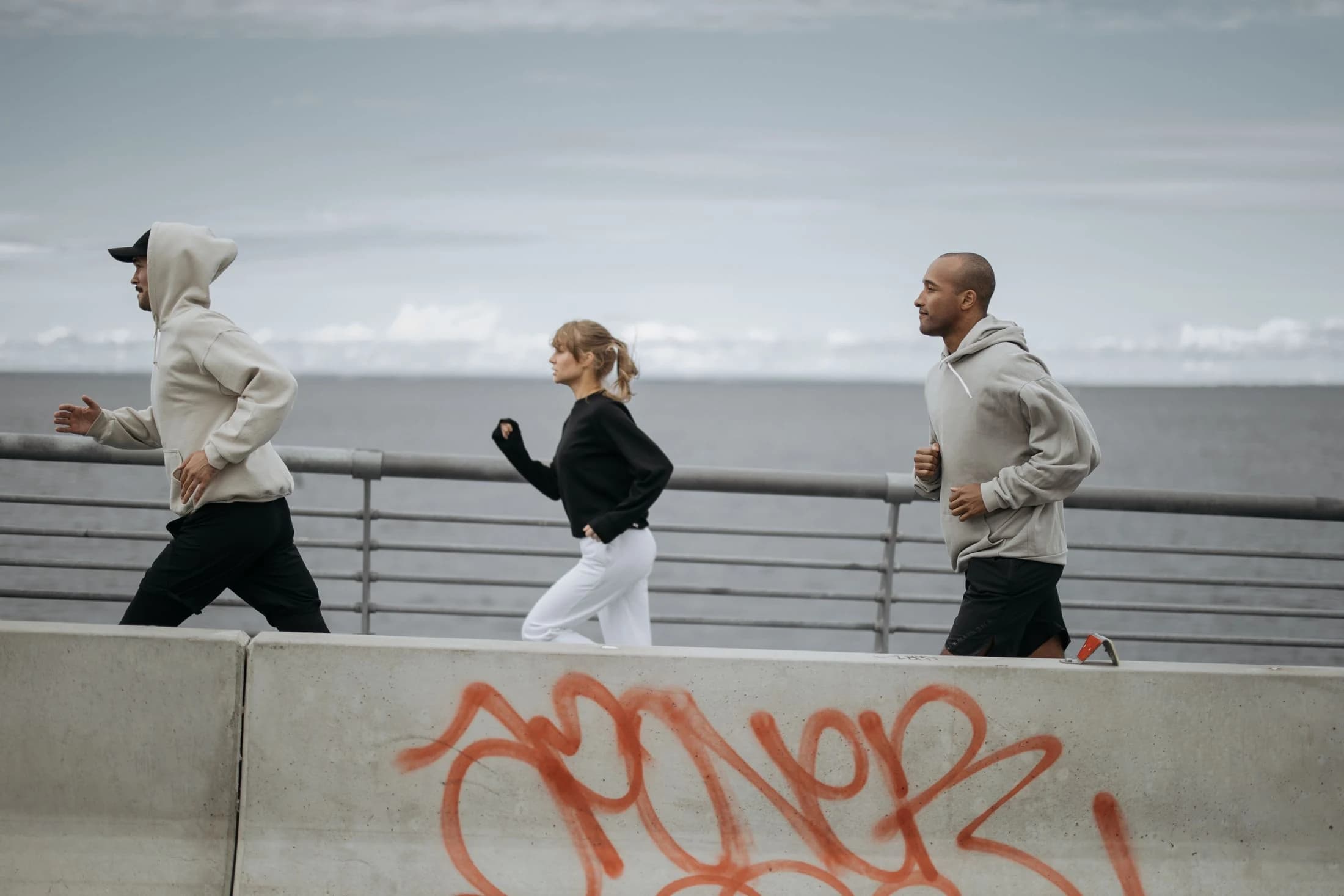 Drei Menschen laufen zusammen an einer Promenade
